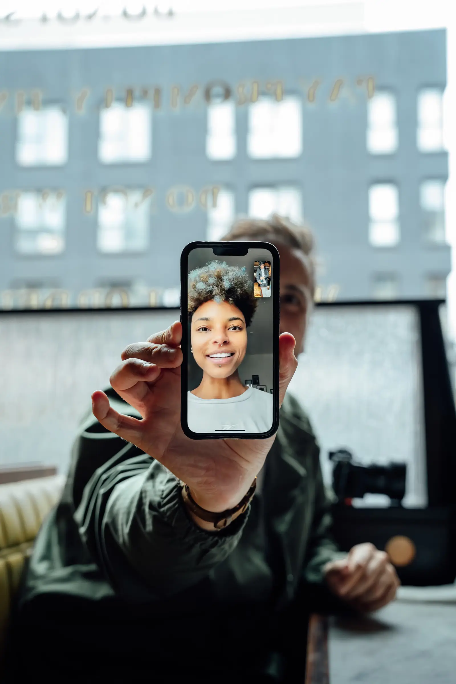 Téléphone tenu face à l’objectif, avec le visage d’une personne en appel vidéo.