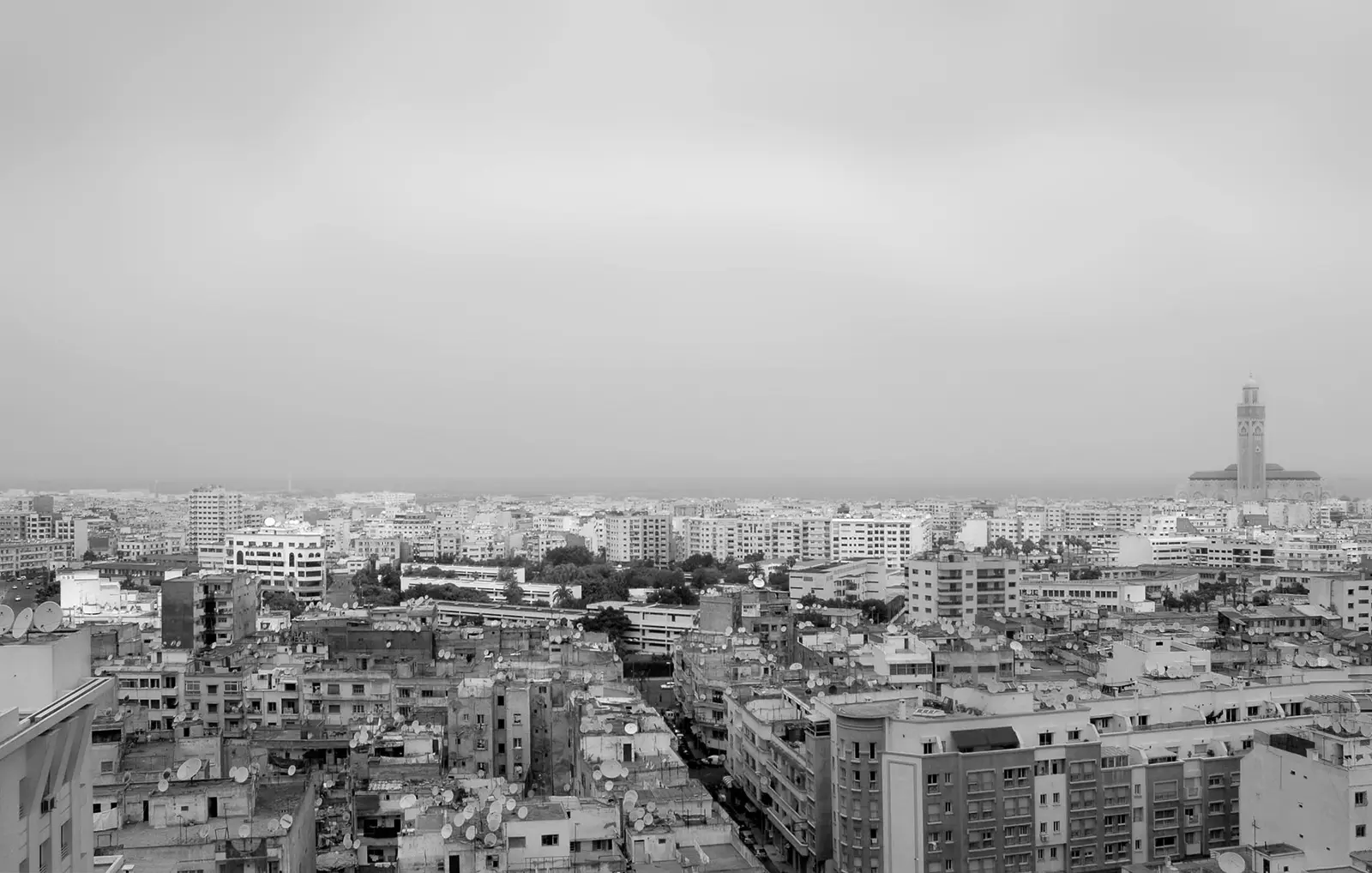 Vue en noir et blanc des toits de Casablanca, minaret de la mosquée Hassan II au loin.