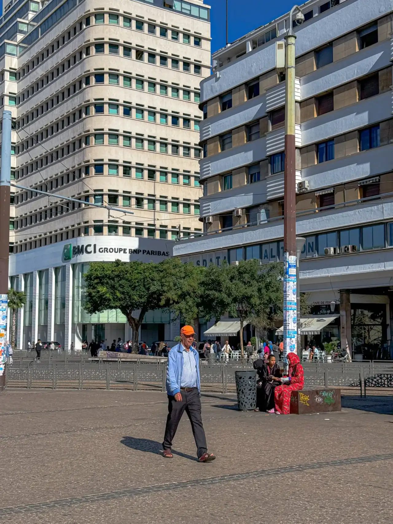 Place à Casablanca, immeubles clairs et passants sous un ciel bleu.